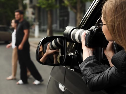 Private detective with camera spying from car